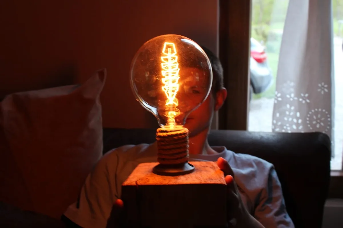 A large light bulb on a wooden base in a dim room